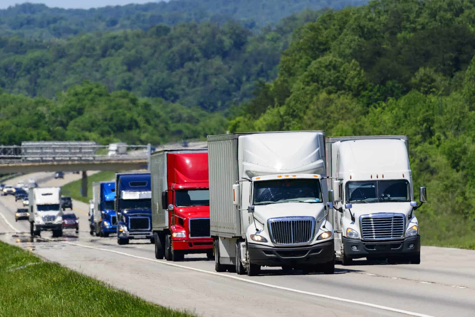 A,Squadron,Of,Eighteen-wheelers,Lead,The,Way,Down,An,Interstate big rig trucks going down a santa clarita highway